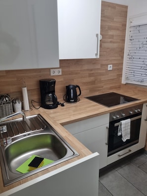 Eine moderne Küche mit Spüle aus Edelstahl, einer Kaffeemaschine, einem Wasserkocher und einem eingebauten Backofen.