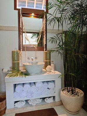 A bathroom with a large sink, a mirror, and a potted plant. - VILLA DUNIA (Gili Trawangan)