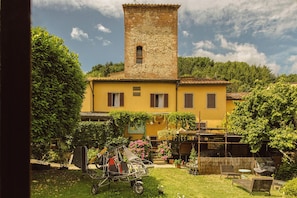 A yellow building with a tower, surrounded by greenery and a garden with outdoor furniture. - Albergo La Felicina  (Scarperia e San Piero)