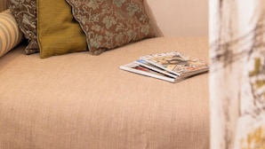 A bedroom with a bed, pillows, a magazine, a mirror, and a hanging light fixture. - Albergo La Felicina  (San Piero A Sieve)