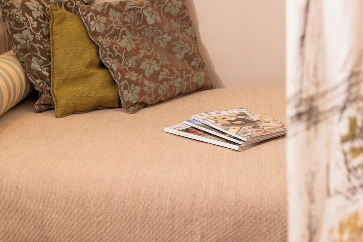 A bedroom with a bed, pillows, a magazine, a mirror, and a hanging light fixture.