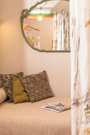 A bedroom with a bed, pillows, a magazine, a mirror, and a hanging light fixture. - Albergo La Felicina  (San Piero A Sieve)