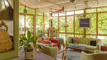A spacious room with large windows, a red airplane model, a green couch, and a table with a vase of flowers.