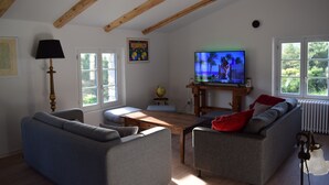Una sala de estar con techo de madera, televisor, sofá, mesa de centro y lámpara.