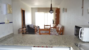 A kitchen with a microwave, a washing machine, and a dining area with a table and chairs. - First Line Apartment With Wifi (Benicarlo)
