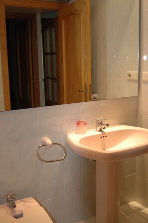 A bathroom with a white sink, a mirror above it, and a wooden door in the background. - First Line Apartment With Wifi (Benicarlo)