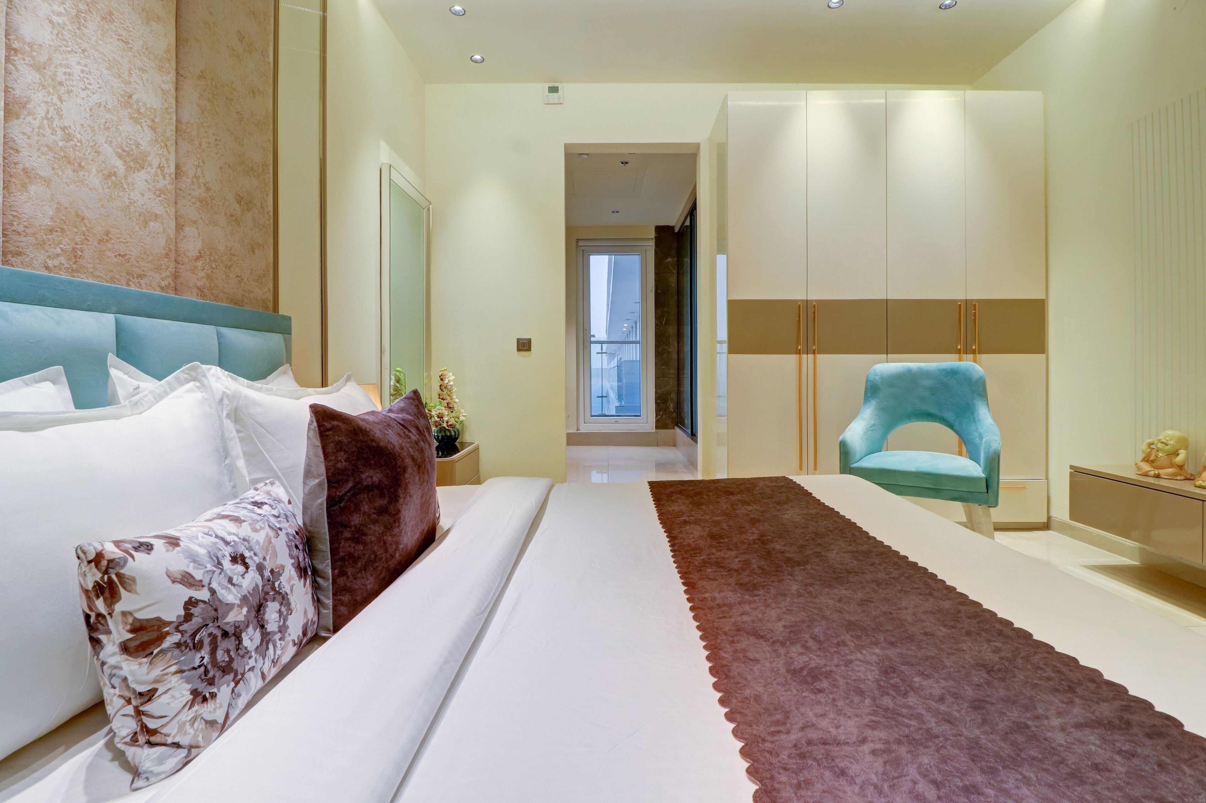 A modern bedroom with a large bed, a blue chair, and a wardrobe.