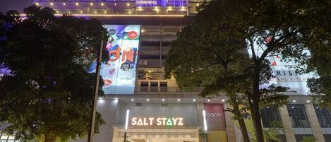 A hotel entrance with a sign reading "SALT STAYZ" and a large billboard advertising a promotion.