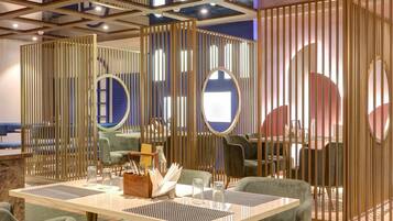 Un comedor moderno con techo alto, diseño geométrico en el techo y una mesa central con sillas.