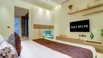 Una habitación de hotel moderna con una cama grande, televisión y escritorio con computadora.