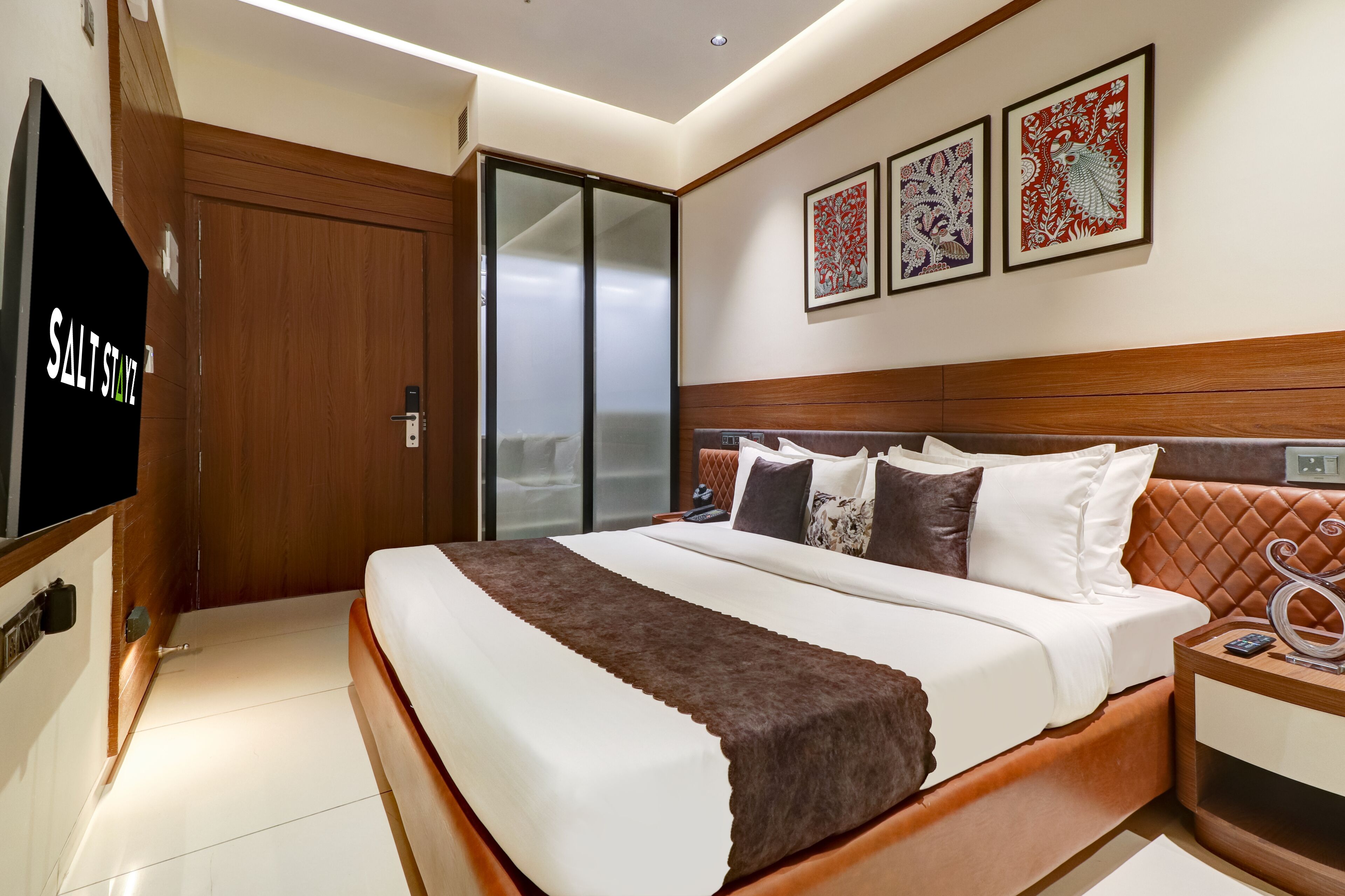 Una habitación de hotel moderna con una cama grande, un televisor y una puerta corrediza a un balcón.