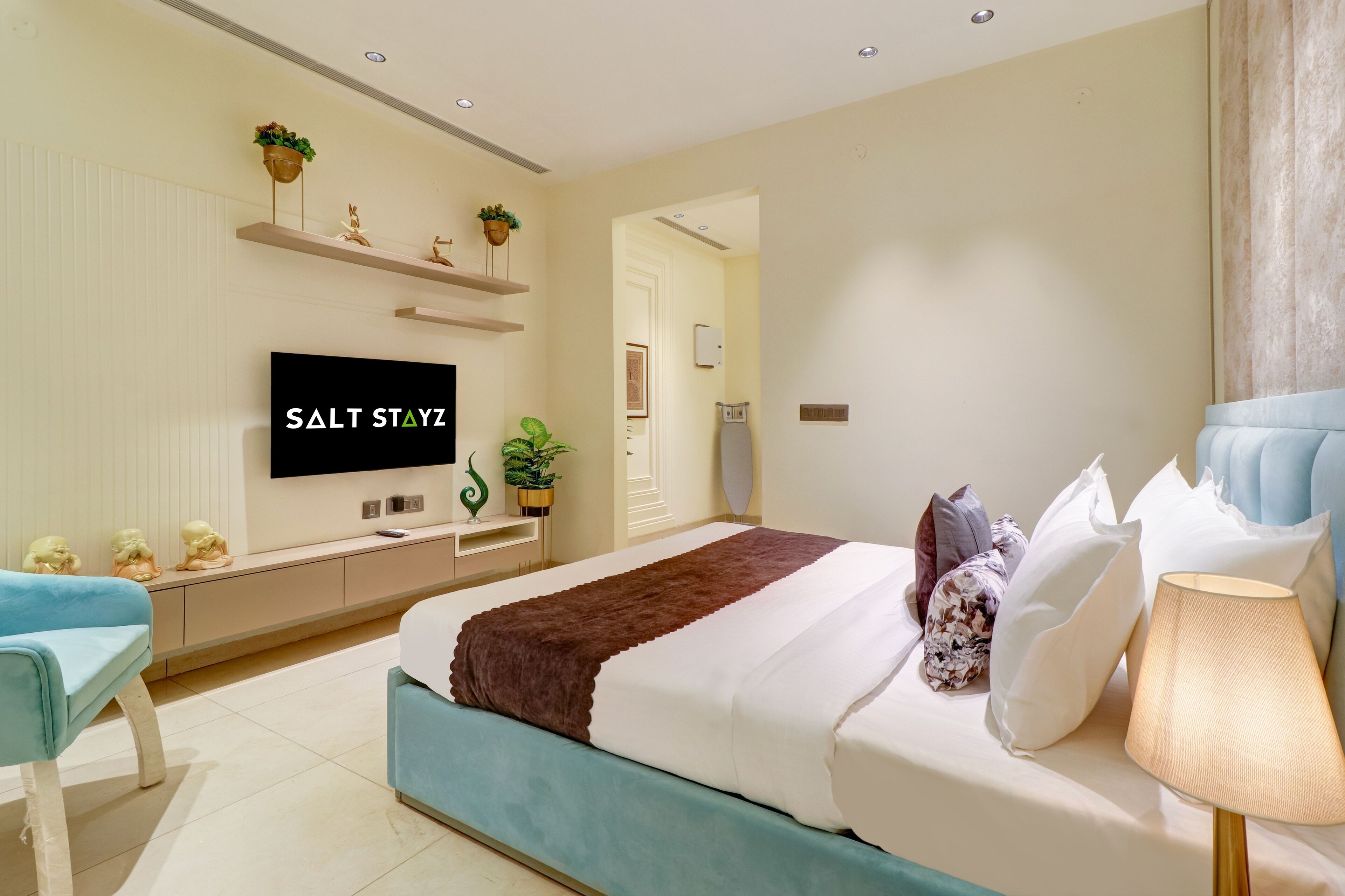 A modern bedroom with a bed, bedside table, lamp, and a TV mounted on the wall.