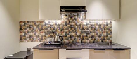 A compact kitchen with a tiled backsplash, a built-in stove, and a refrigerator.