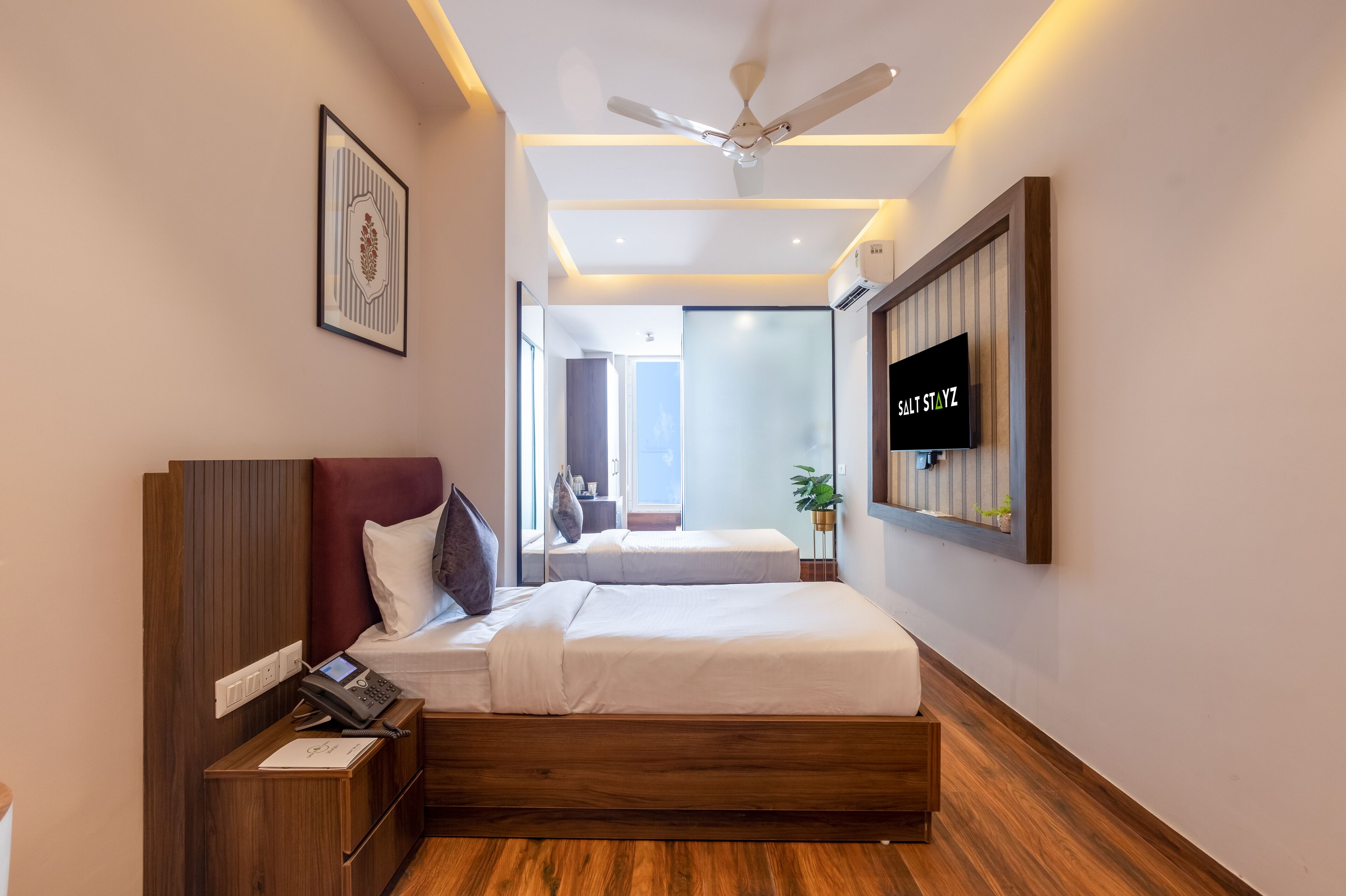 A modern hotel room with a bed, bedside table, and a mounted television.