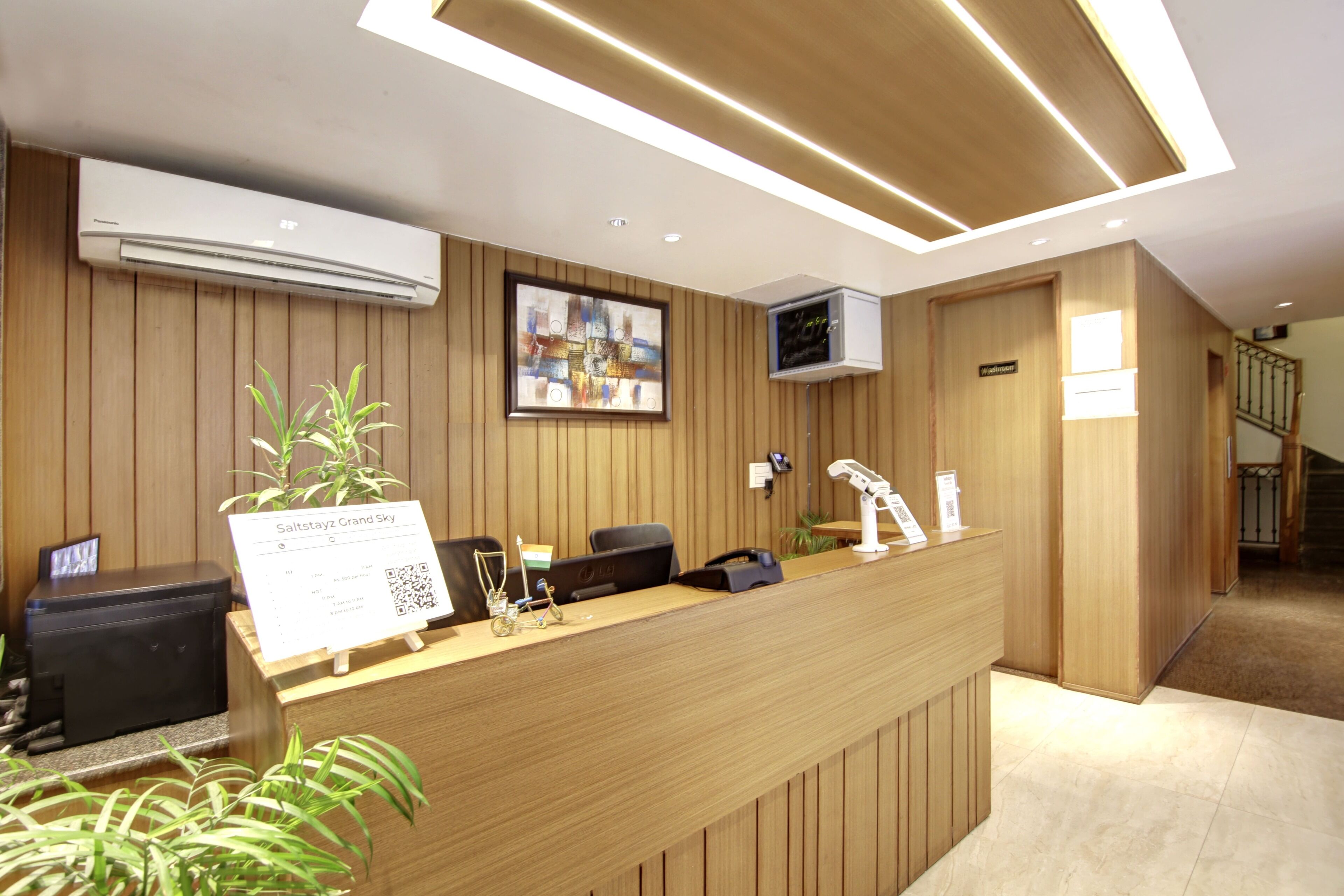 A reception desk with a sign, a computer, a telephone, and a small plant.