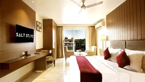 Une chambre d’hôtel avec un lit, un bureau, une télévision et une vue sur l’extérieur.