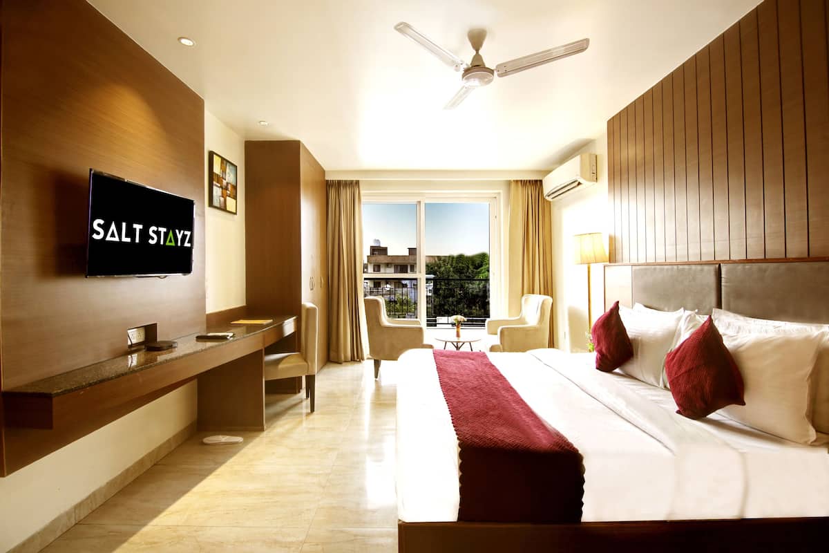 Une chambre d’hôtel avec un lit, un bureau, une télévision et une vue sur l’extérieur.