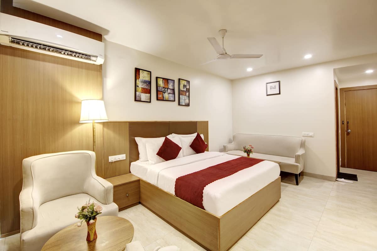 Une chambre d’hôtel avec un lit, une chaise, une table de chevet, une lampe et un ventilateur de plafond.
