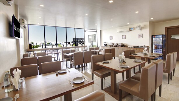 Un espace repas moderne avec des tables et des chaises, une cuisine en arrière-plan et un réfrigérateur de la marque Pepsi.