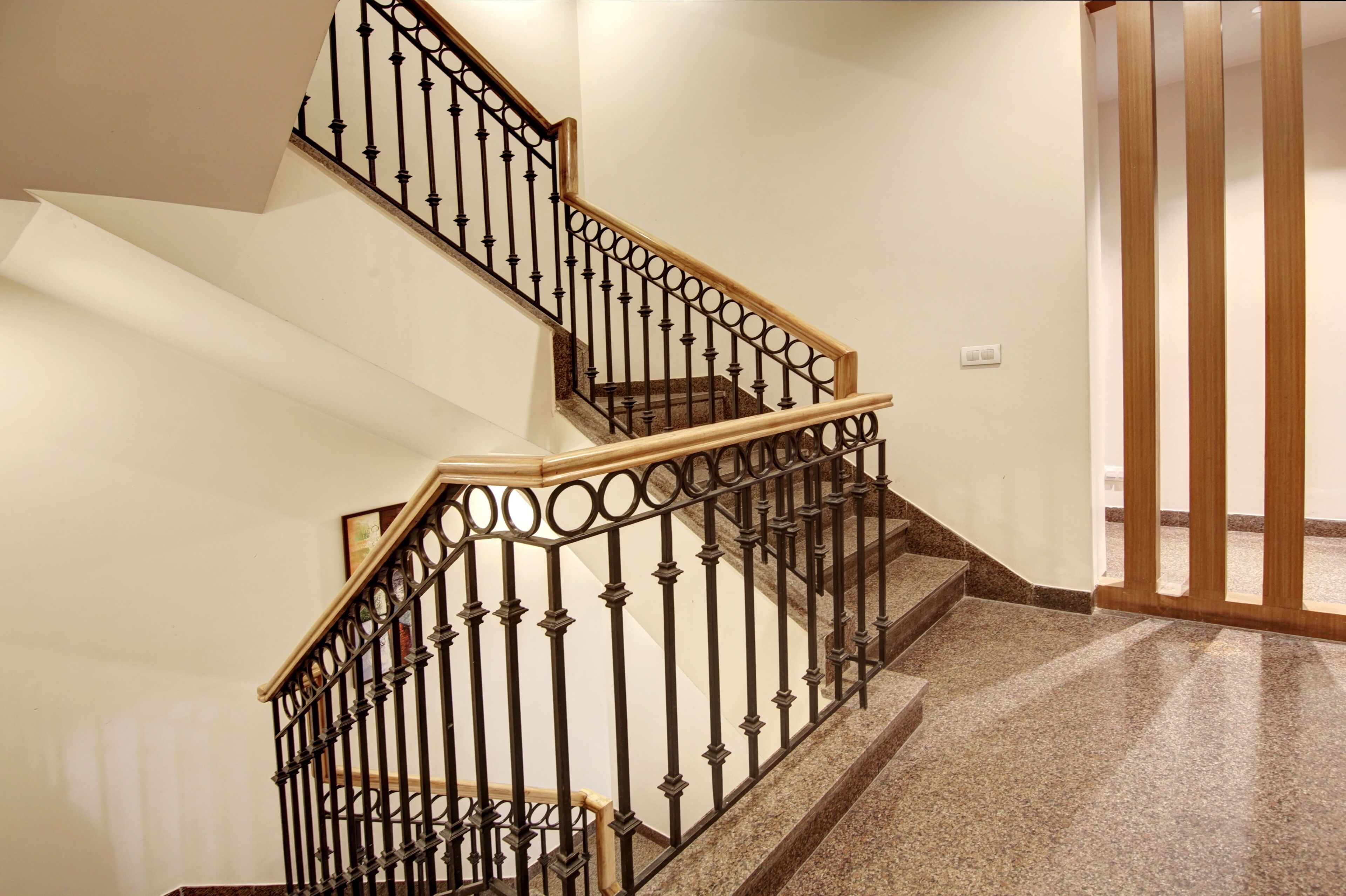A staircase with a black wrought iron railing and wooden handrails, leading to an upper floor.
