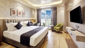 A modern hotel room with a large bed, a desk, a green armchair, and a flat-screen TV. - Saltstayz Premier - Near Golf Course Road & Sector 57 (Gurugram)