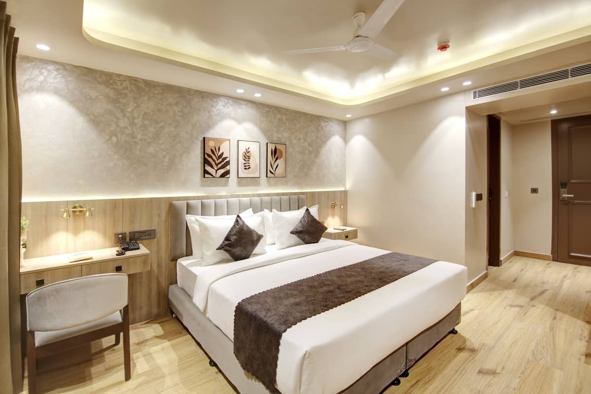 A modern hotel room with a large bed, bedside tables, a desk, and a chair.