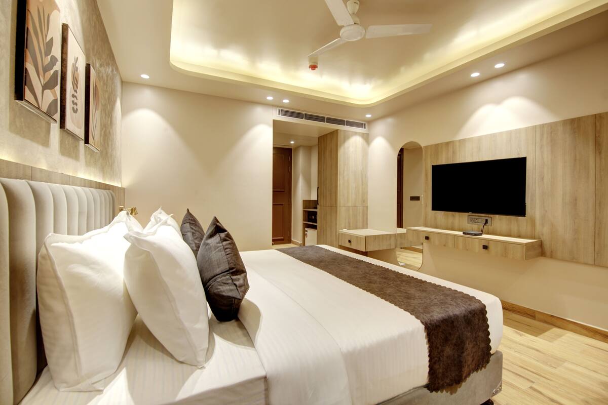 A modern bedroom with a large bed, a flat-screen TV, and a ceiling fan.