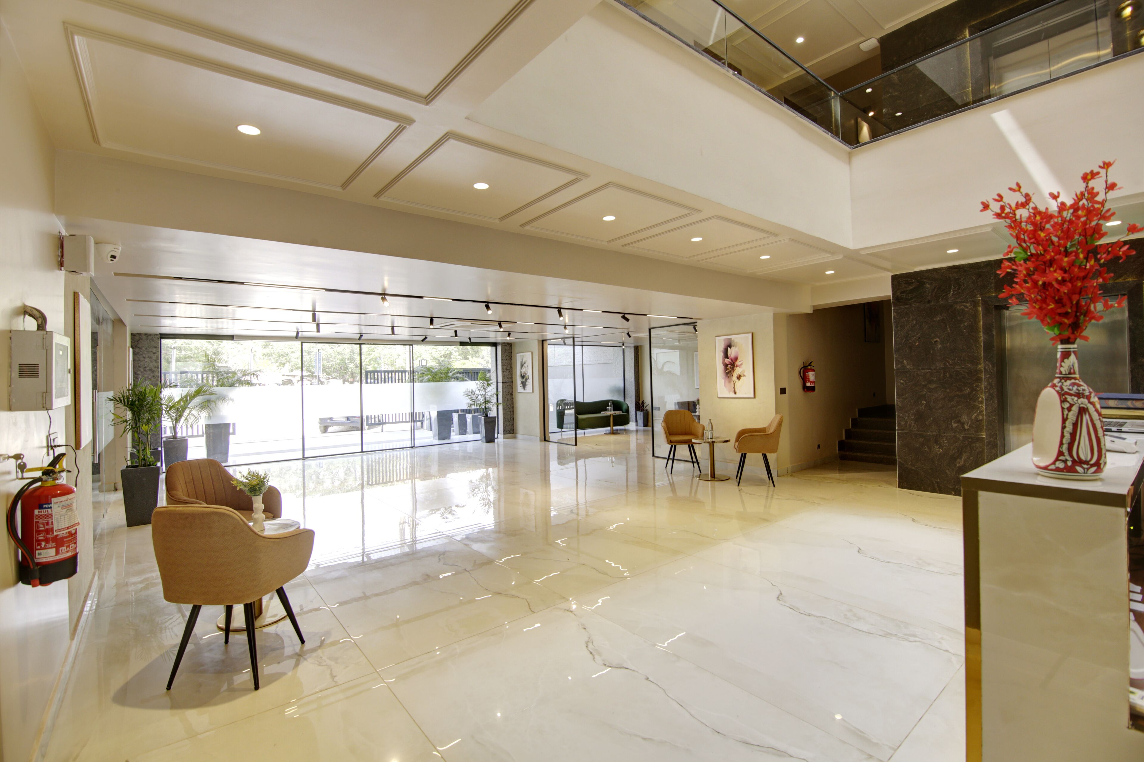 A spacious lobby with a high ceiling, a glass entrance, and a fire extinguisher on the wall.