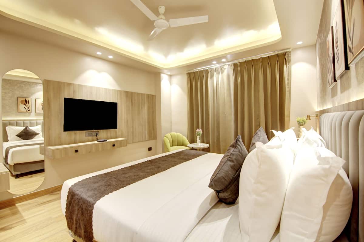 A modern hotel room with a large bed, a flat-screen TV, a ceiling fan, and a seating area with a chair and a small table.