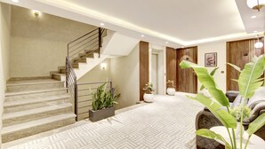 Un interior moderno con una escalera, una sala de estar con sofá y una planta grande.