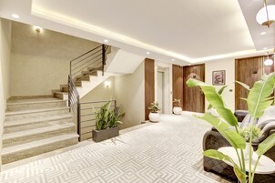 Un interior moderno con una escalera, una sala de estar con sofá y una planta grande.
