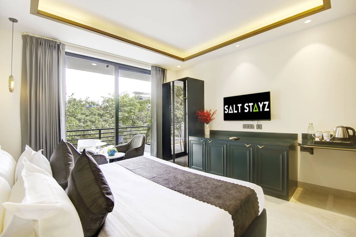 Ein modernes Hotelzimmer mit einem großen Bett, einem Schreibtisch und einem an der Wand befestigten Fernseher.