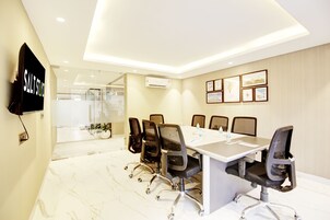 A conference room with a long table, six chairs, a TV, and framed pictures on the wall.
