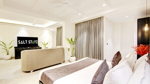 Una habitación de hotel moderna con una cama grande, un sofá, un televisor y un ventilador de techo.