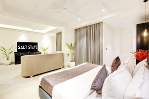 Una habitación de hotel moderna con una cama grande, un sofá, un televisor y un ventilador de techo.