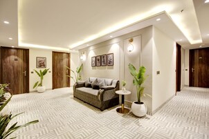 Un moderno vestíbulo de hotel con piso estampado, un sofá, plantas en macetas y obras de arte enmarcadas en las paredes.