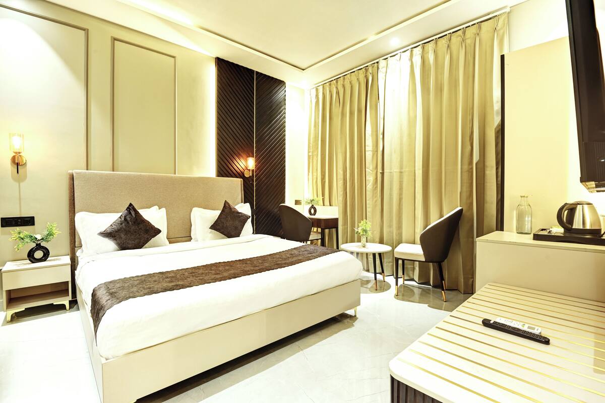 Ein Hotelzimmer mit einem großen Bett, Nachttischen, einem Schreibtisch, einem Sessel und einem Fernseher.