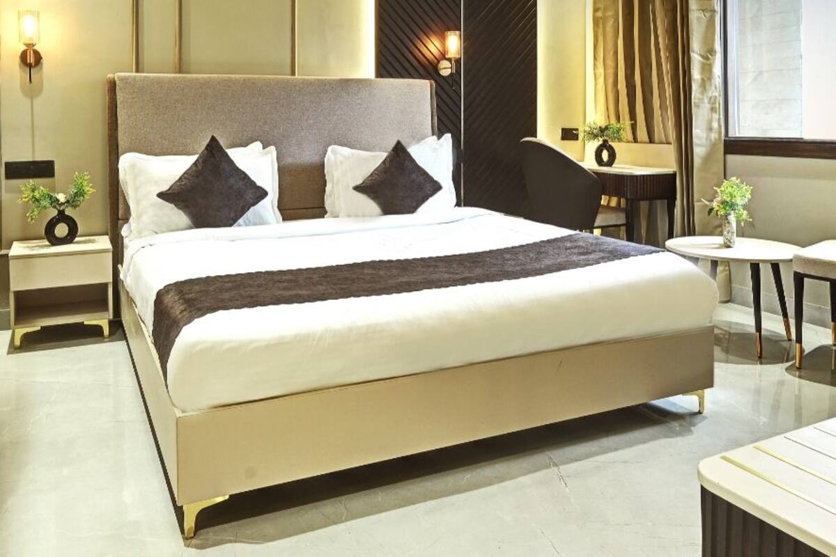 Ein Hotelzimmer mit einem großen Bett, Nachttischen, einem kleinen runden Tisch, einem Sessel und einem Schreibtisch mit Stuhl.