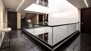 A modern hotel lobby with a glass railing, a staircase, and a minimalist design. - Saltstayz Premier – Golf Course Road & Sector 42 (Gurugram)