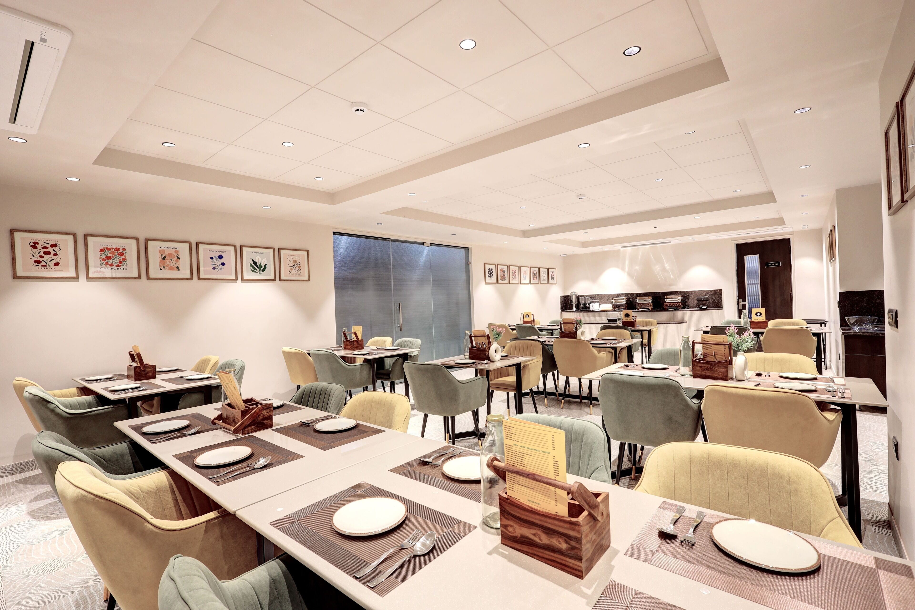A modern dining area with multiple tables, chairs, and a kitchen in the background.