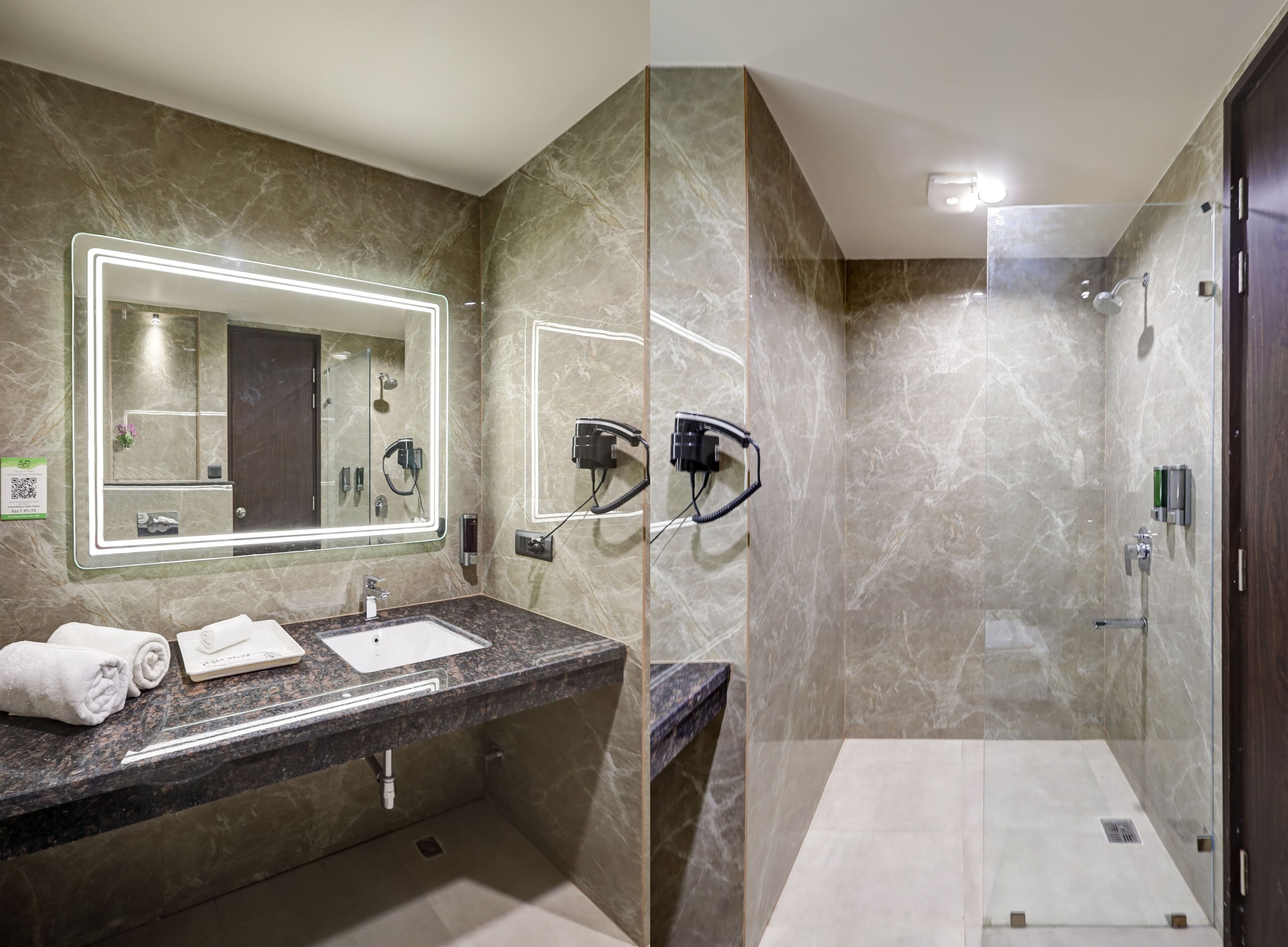 Un baño moderno con tocador de mármol, un espejo grande, ducha y un secador de pelo montado en la pared.