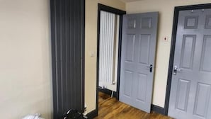 Una habitación de hotel con piso de madera, una cortina negra y dos puertas grises.