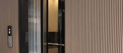 An elevator with a metallic finish and a red carpet at the entrance.