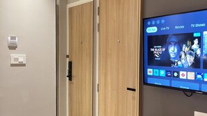 A modern hotel room with a wooden wardrobe, a built-in TV displaying a movie, and a mirror. - AXON Bellandur by AXON Hotels (Bengaluru)