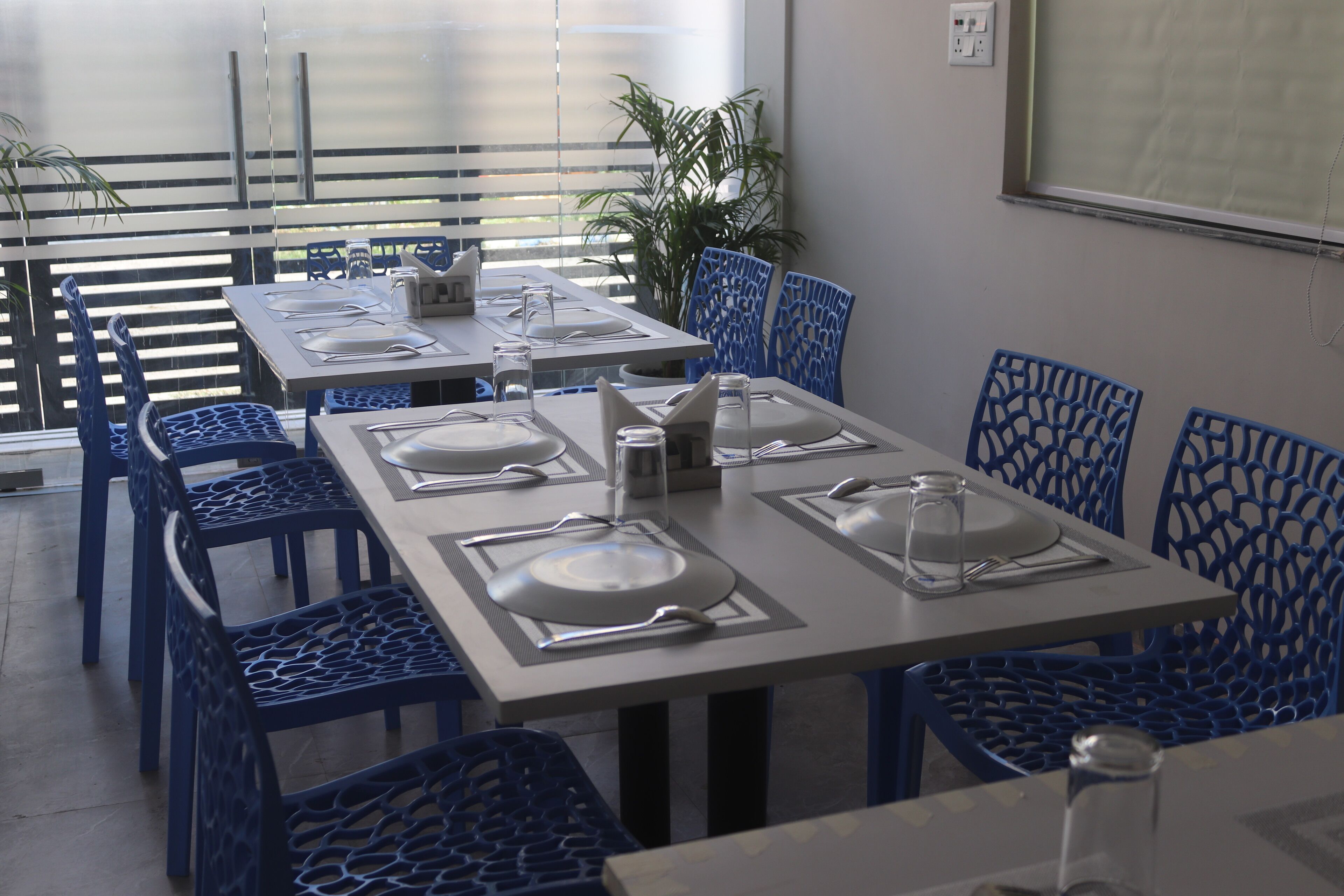 A dining area with blue chairs and tables set for four.