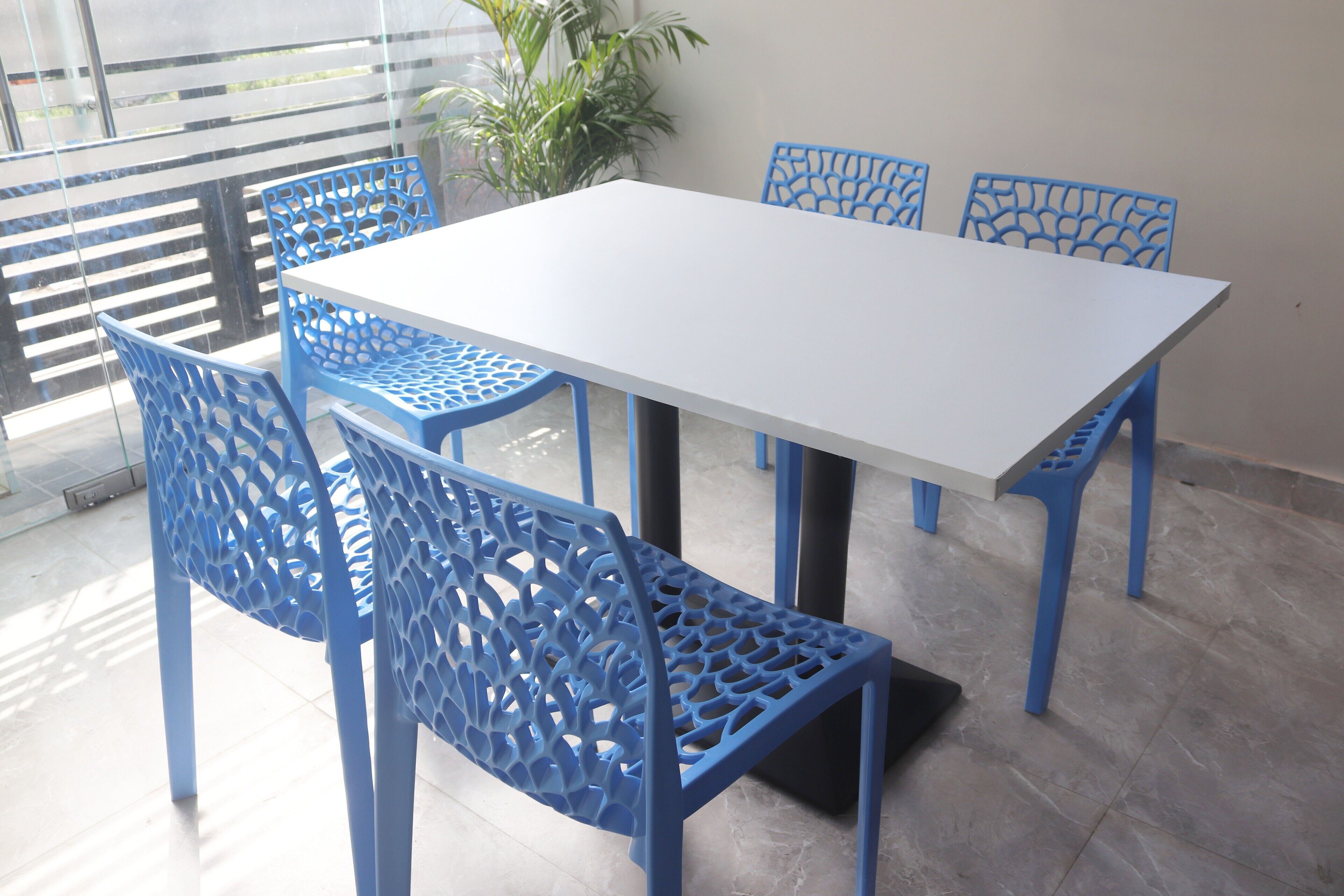 Un comedor con mesa blanca y sillas azules con detalles tallados.