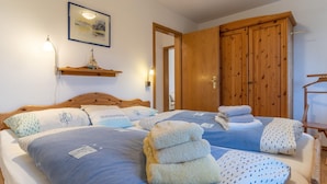Ein Schlafzimmer mit zwei Betten, einem Holzschrank und einem gerahmten Bild an der Wand.