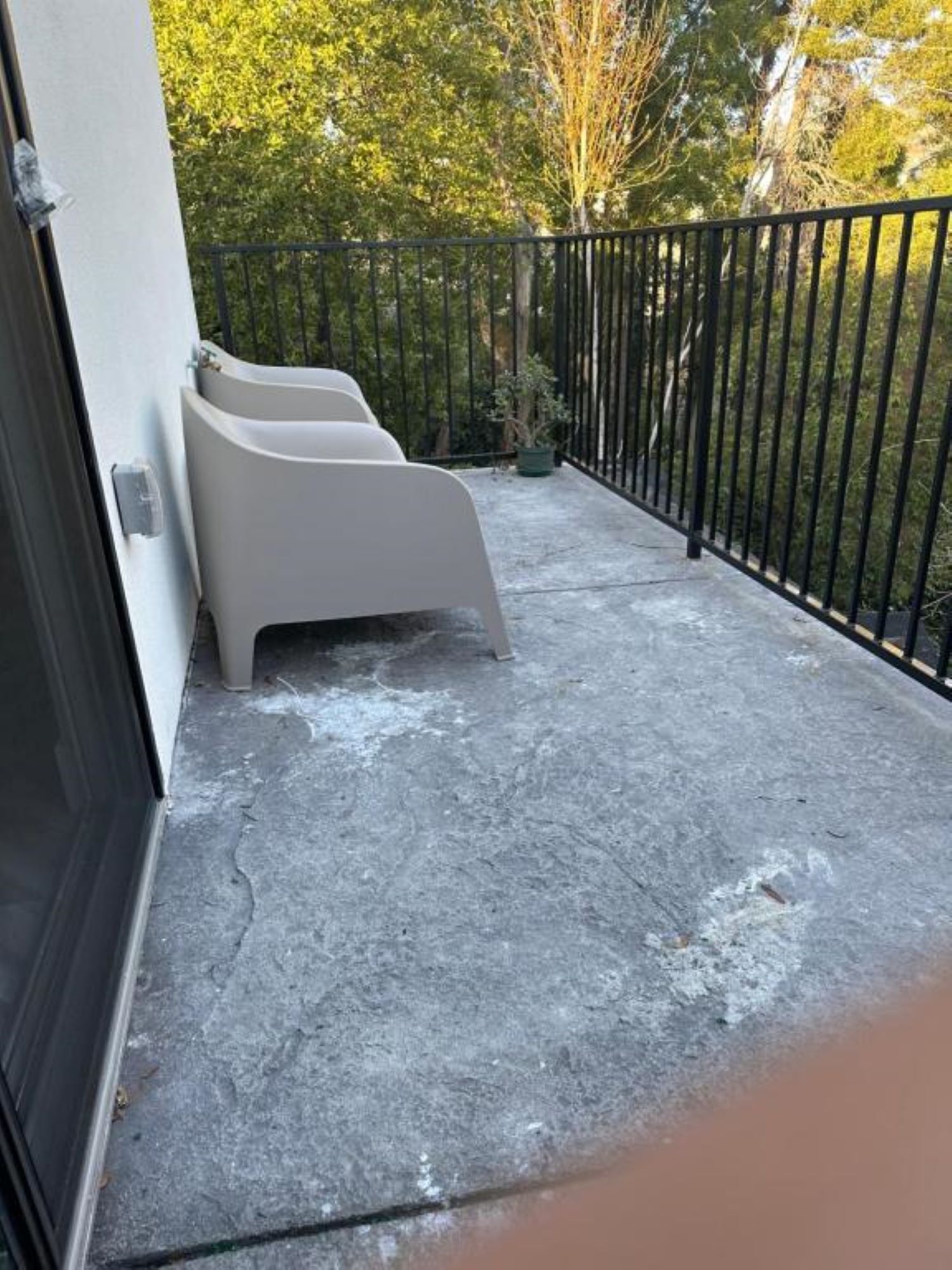 Parvekkeessa on betonilattia, musta metallikaide ja kaksi valkoista tuolia.