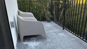 Parvekkeessa on betonilattia, musta metallikaide ja kaksi valkoista tuolia.
