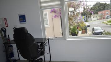 A room with a view of a street, a desk, a chair, and a fire exit sign.